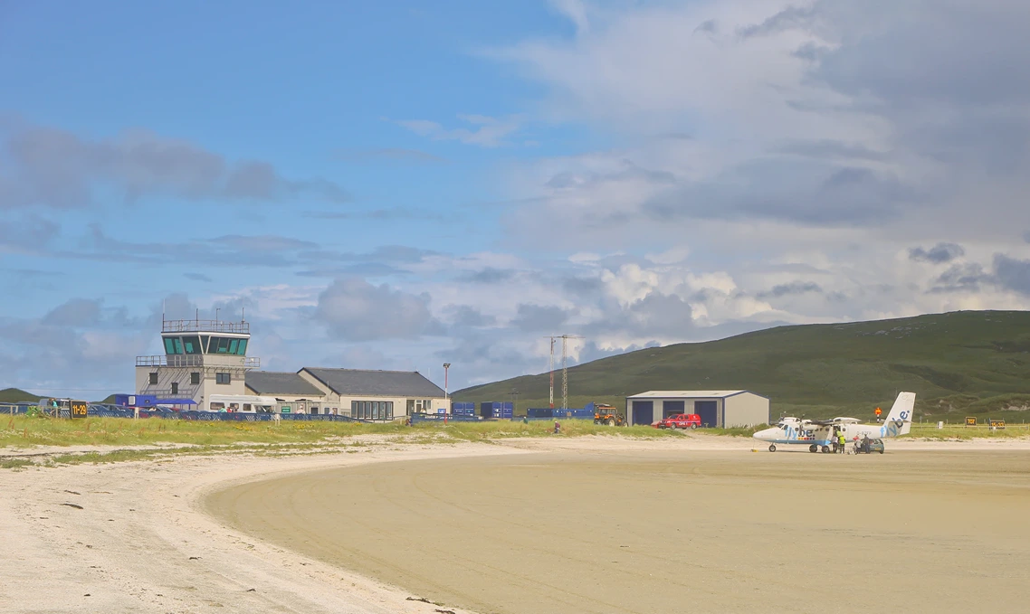 Barra, Scotland, UK.-August 1, 2014: Panorama of the Barra Airport with one airplane, a Twin Otter, parked in front and beach in the foreground
